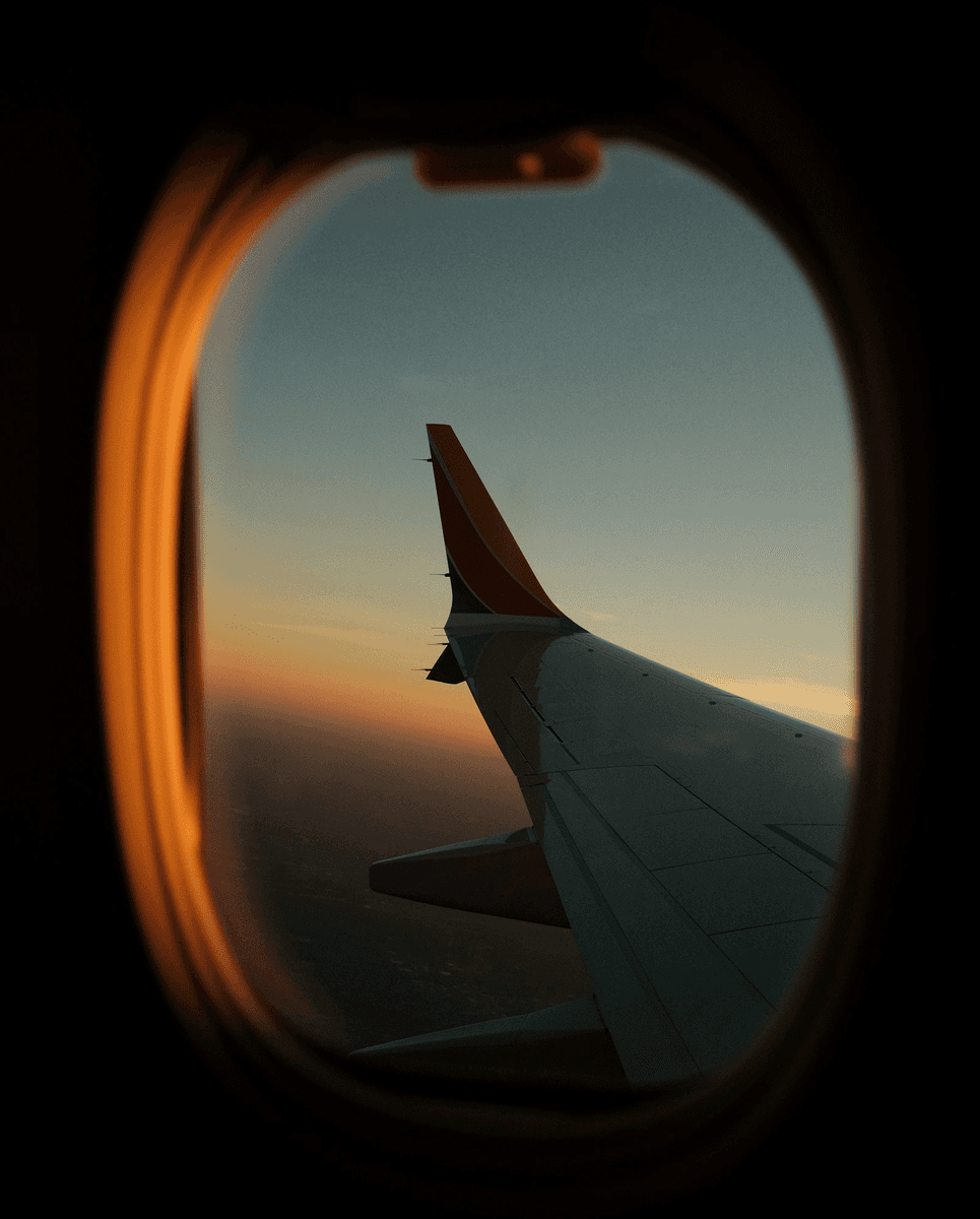 View of an airplane wing through a window at sunset
