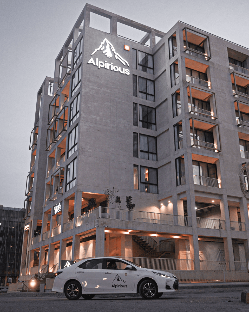 Alpirious hotel building at dusk with a branded car